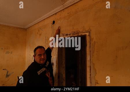 Alfafar, Spanien - 19. November 2024. Vicente, wohnhaft in Alfafar an der Torrente Avenue vor dem parque Alcosa, ließ sein Haus vollständig vom Wasserstrom untertauchen. Er zeigt die Höhe, die durch die Flut erreicht wurde, und zwei Fotos, die von derselben Stelle aufgenommen wurden, zum Fenster und zu den Straßenverhältnissen. In weniger als 15 Minuten stieg das Wasser um mehr als 1 Meter und das Motorrad (auf dem Foto) wurde weggefegt. Zu diesem Zeitpunkt hatten die Behörden noch nicht den roten Alarm gemeldet. Quelle: Roberto Arosio/Alamy Live News Stockfoto