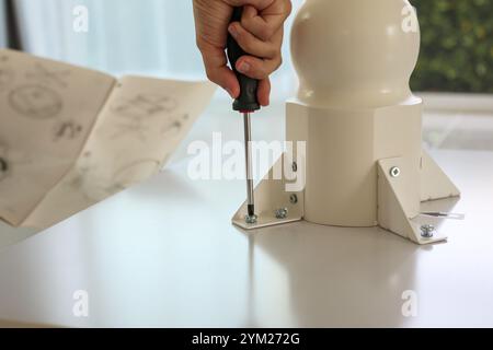 Asiatischer Mann, der weiße Tischmöbel zu Hause zusammenbaut Stockfoto