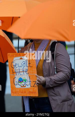 Magdeburg, Deutschland. November 2024. "Gewaltbeihilfegesetz muss kommen" steht auf einem Schild einer Teilnehmerin einer Kampagne des Frauenrates Sachsen-Anhalt. Dutzende Frauen und Männer mit orangefarbenen Regenschirmen standen vor dem landtag Sachsen-Anhalts. Mit der Aktion des Landesfrauenrates Sachsen-Anhalt zum Internationalen Tag gegen Gewalt gegen Frauen soll auf die Notwendigkeit hingewiesen werden, das Gewaltbeihilfegesetz auf Bundesebene zu verabschieden. Die Regenschirme symbolisierten den Schutz vor Gewalt gegen Frauen. Quelle: Klaus-Dietmar Gabbert/dpa/Alamy Live News Stockfoto