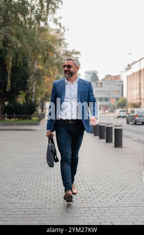 Ein gutaussehender reifer Geschäftsmann läuft durch die Straße der Stadt. Stockfoto