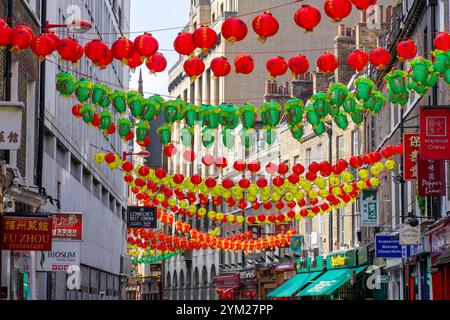 Farbenfrohe Laternen hängen auf der anderen Straßenseite in Chinatown, London. Rote, grüne, gelbe und kunstvolle Laternen. Einige Straßenschilder sind sichtbar Stockfoto