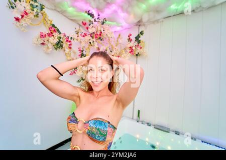 Lächelnde Frau im Badeanzug im Spa mit Blumendekoration Stockfoto