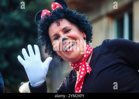 Eine Person in einem Kostüm, das Minnie Mouse ähnelt, einer bekannten Zeichentrickfigur. Ein schwarzes Oberteil, ein rotes Stirnband mit Polka Dots und Maus Stockfoto