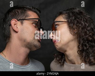 Ein Mann und eine Frau sehen sich genau an, machen lustige und amüsante Gesichter Stockfoto