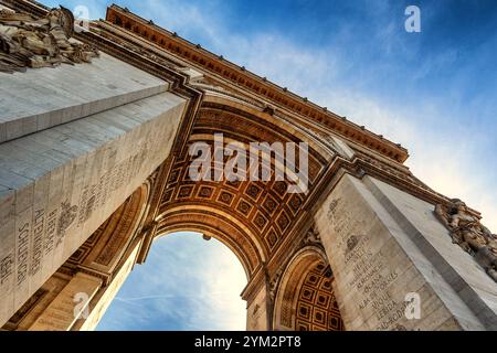 Ein beeindruckender Blick von unten auf den Arc de Triomphe in Paris, Frankreich. Das Foto zeigt die detaillierten Reliefs und Gravuren der Säulen sowie die kunstvolle Deckenverzierung des Triumphbogens. Der klare, blaue Himmel im Hintergrund verstärkt die majestätische Wirkung dieses ikonischen Wahrzeichens, das ein Symbol für französische Geschichte und Architektur ist. *** Ein beeindruckender Blick von unten auf den Triumphbogen in Paris, Frankreich das Foto zeigt die detaillierten Reliefs und Stiche der Säulen sowie die kunstvolle Deckendekoration des Triumphbogens, in dem der klare blaue Himmel steht Stockfoto