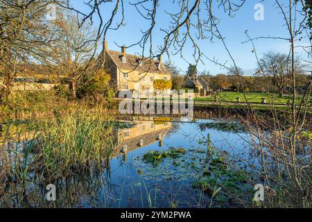 Abendlicht auf der College Farm neben dem Teich auf dem Grün im Dorf Cotswold in Wyck Rissington, Gloucestershire, England Großbritannien Stockfoto