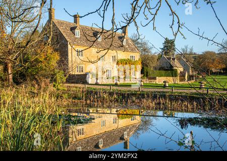 Abendlicht auf der College Farm neben dem Teich auf dem Grün im Dorf Cotswold in Wyck Rissington, Gloucestershire, England Großbritannien Stockfoto