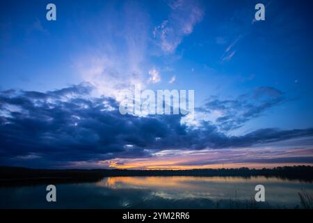 Ein atemberaubend schöner Sonnenuntergang über einem ruhigen See mit dramatischen Wolken über uns Stockfoto