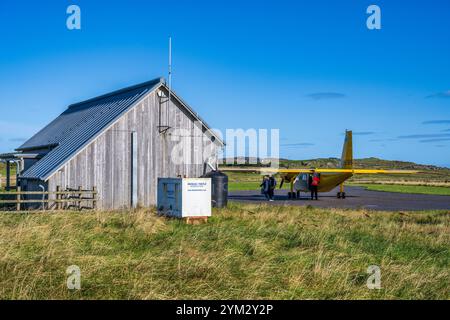 Passagiere, die von Hebridean Air Services Britten-Norman BN-2B Islander am Coll Flugplatz, Isle of Coll, Innere Hebriden, Schottland, Großbritannien aussteigen Stockfoto