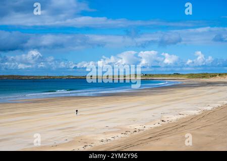 Eine Einzelfigur überquert den goldenen Sand des Crossapol Beach auf der Isle of Coll, Innere Hebriden, Schottland, Großbritannien Stockfoto