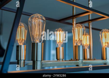 Eine Reihe von Glühbirnen wird beleuchtet, was eine warme und einladende Atmosphäre schafft. Die Glühlampen sind so angeordnet, dass sie gleichmäßig angeordnet und zugewandt sind Stockfoto