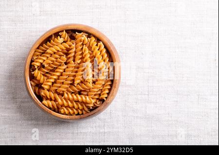 Kichererbsen-Spiralnudeln in einer Holzschale, mit leerem Platz für Text. Kleine Fusilli, eine Nudelsorte in Spiralform oder Korkenzieher-Form. Stockfoto
