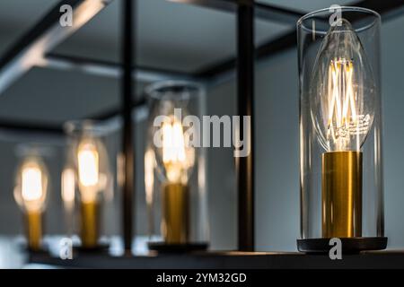 Eine Reihe von Glühbirnen wird beleuchtet, was eine warme und einladende Atmosphäre schafft. Die Glühlampen sind in Klarglashaltern untergebracht, was einen Hauch von Eleganz verleiht Stockfoto