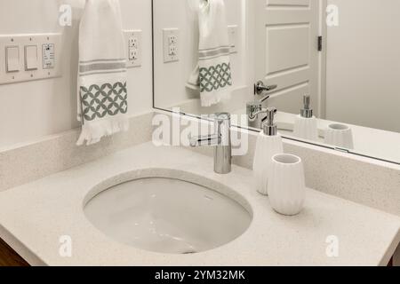 Ein Waschbecken im Bad mit einem Handtuch darüber. Das Waschbecken ist weiß und das Handtuch weiß und blau Stockfoto