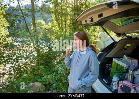 Frau im Wald, die Zähne putzt an einem friedlichen Morgen. Frau, die im Wald campt, putzt sich die Zähne in einem Auto auf einem friedlichen Stockfoto