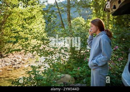 Frau im Wald, die Zähne putzt an einem friedlichen Morgen. Frau, die im Wald campt, putzt sich die Zähne in einem Auto auf einem friedlichen Stockfoto