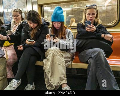 Abgelenkte Gen Z-Reisende in der New Yorker U-Bahn am Sonntag, den 17. November 2024. (© Richard B. Levine) Stockfoto