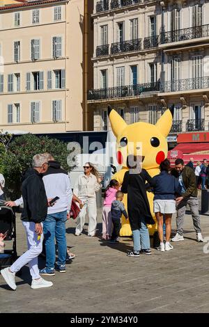 Marseille. Frankreich - 20. November 2024: Pikachu Maskottchen interagiert mit Kindern im alten Hafen von Marseille. Die Menschen genießen die lebhafte Atmosphäre Stockfoto