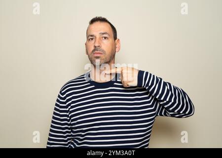 Ein bärtiger hispanischer Mann droht, sich die Kehle zu durchschneiden. Der Mann sieht gewalttätig aus und macht bedrohliche Gesten. Der Mann droht und sucht nach einem Kampf Stockfoto