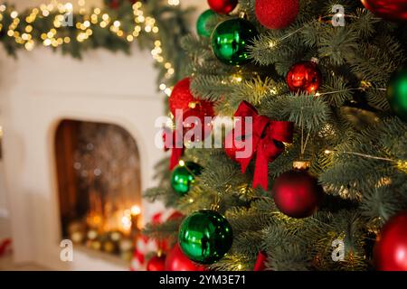Weihnachtsrote Schleife auf einem Baum, Nahaufnahme, vor dem Hintergrund eines Kamins, stilvolle Neujahrsdekoration Stockfoto