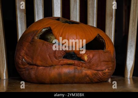 Verfaulender großer Jack-o-Laterne Kürbis auf einem Stuhl Stockfoto