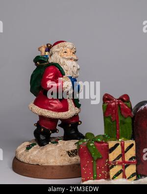 Weihnachtsmann-Figur mit Tasche und vor großen weihnachtskisten Stockfoto