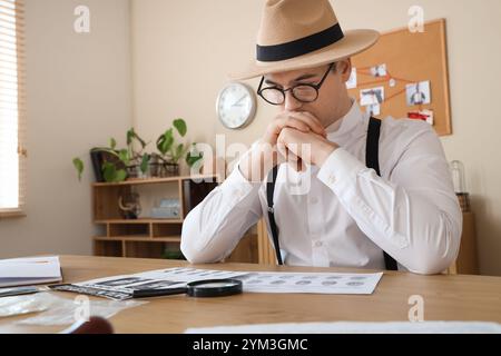 Männlicher Detective mit Fingerabdrücken, der den Fall am Tisch im Büro untersucht Stockfoto