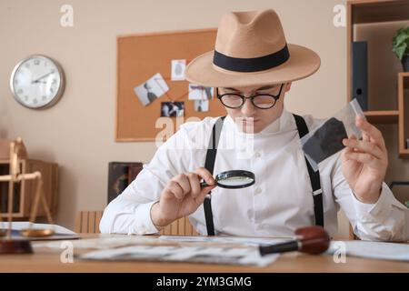 Männlicher Detektiv mit Lupe untersucht den Fall am Tisch im Büro Stockfoto