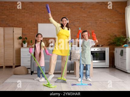 Mutter und ihre Kinder in Kopfhörern haben Spaß beim Reinigen zu Hause Stockfoto