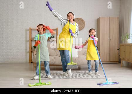 Mutter und ihre Kinder in Kopfhörern haben Spaß beim Reinigen zu Hause Stockfoto