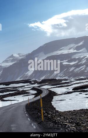 Ein faszinierender Blick auf schneebedeckte Straßen, die sich durch isländische Berge schlängeln, umgeben von eisigen Gipfeln und arktischer Wildnis Stockfoto