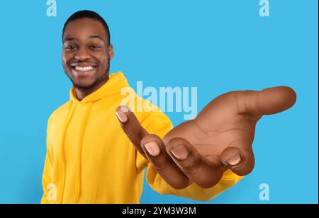 Glücklicher schwarzer Kerl, der große ausgestreckte Hand zeigt, Hilfe anbietet, etwas nimmt oder gibt und nach Unterstützung greift Stockfoto