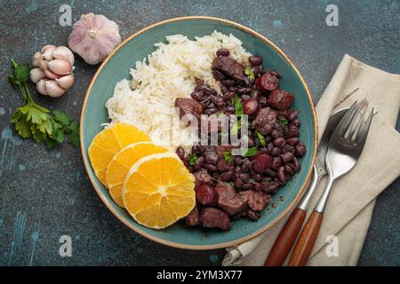 Feijoada, traditioneller brasilianischer Eintopf mit schwarzen Bohnen, Reis und Orangenscheiben, Blick von oben Stockfoto