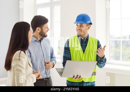 Foreman Spricht Über Das Projekt Zur Renovierung Von Häusern Mit Einem Paar, Das Laptop Verwendet Stockfoto