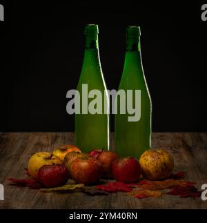 Zwei Flaschen Apfelwein zwischen einem Haufen Äpfel Stockfoto