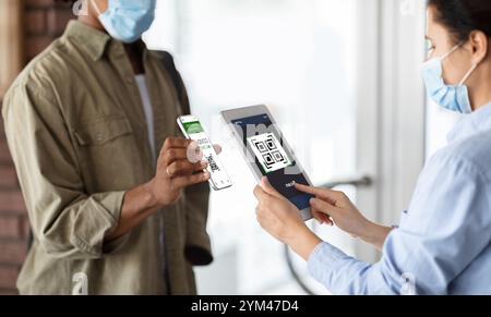 Weibliche Mitarbeiterin mit digitalem Tablet Scanning Health QR-Code des männlichen Besuchers Stockfoto