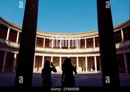 Besucher bewundern den kreisrunden Innenhof des Palastes Karls V. in der Alhambra, der von hohen Steinsäulen eingerahmt wird Stockfoto