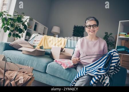 Foto von fröhlicher glücklicher Dame tragen rosafarbenes Sweatshirt genießt, neue Kleidung bestellen zu bekommen drinnen Zimmer Haus Haus Stockfoto