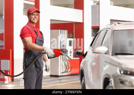 Arbeiter, der an einer Tankstelle einen SUV mit Kraftstoff betankt Stockfoto