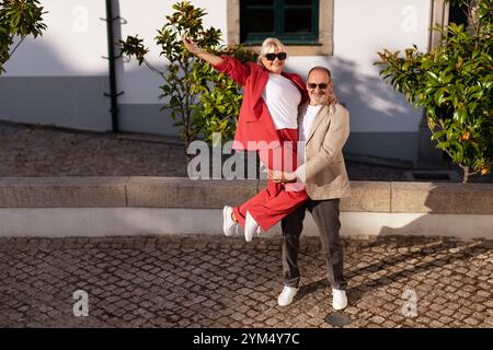 Das liebende Paar genießt einen fröhlichen Moment, während es draußen in hellen Gewändern posiert Stockfoto
