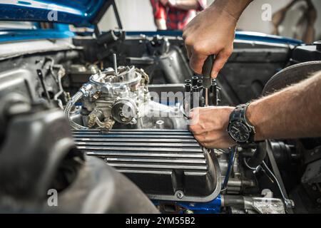 Eine Person arbeitet an einem Motor in einer Werkstatt und verwendet Werkzeuge zum Festziehen von Komponenten. Der Schwerpunkt liegt auf den komplizierten Details der Motorbaugruppe. Stockfoto