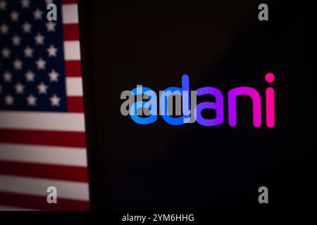 Das Firmenlogo von Adani mit US-Flagge im Hintergrund symbolisiert die wachsende Präsenz der Adani Group unter der rechtlichen und politischen Kontrolle der USA Stockfoto
