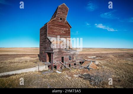 Ein großes, altes, verlassenes Gebäude mit einem schrägen Dach. Das Gebäude ist von einer trockenen, kargen Landschaft umgeben Stockfoto