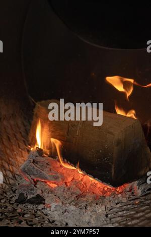 Nahaufnahme des glühenden Holzfeuers in einer Räuchergrillbox mit lebhaften Flammen, schwelender Glut und rustikalen Texturen, perfekt für Grillen und Kochen im Freien Stockfoto