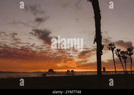 Huntington Beach Pier bei Sonnenuntergang mit pulsierendem Himmel, ruhigen Wellen und ikonischem Küstencharme. Ein atemberaubendes kalifornisches Reiseziel in Surf City, USA. Stockfoto