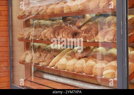 Eine wunderschöne Auswahl an frisch gebackenem Brot wird verführerisch in einem Bäckereifenster gezeigt Stockfoto