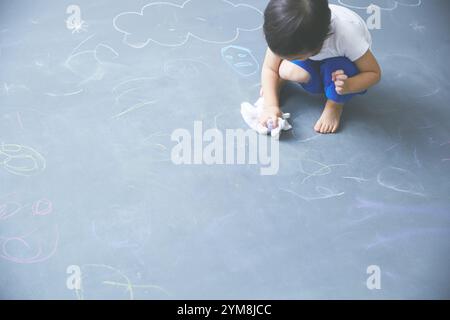 Nahaufnahme eines Jungen, der Graffiti auf großer Tafel löscht Stockfoto