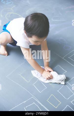 Nahaufnahme eines Jungen, der Graffiti auf großer Tafel löscht Stockfoto