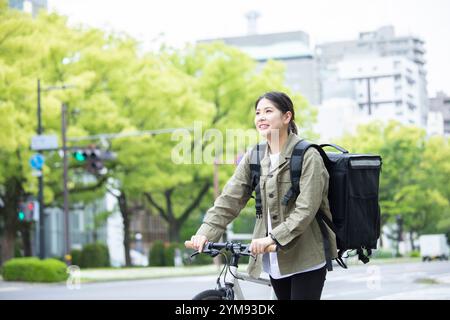 Eine junge Frau, die Pakete mit dem Fahrrad liefert Stockfoto