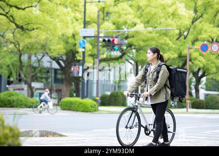 Eine junge Frau, die Pakete mit dem Fahrrad liefert Stockfoto